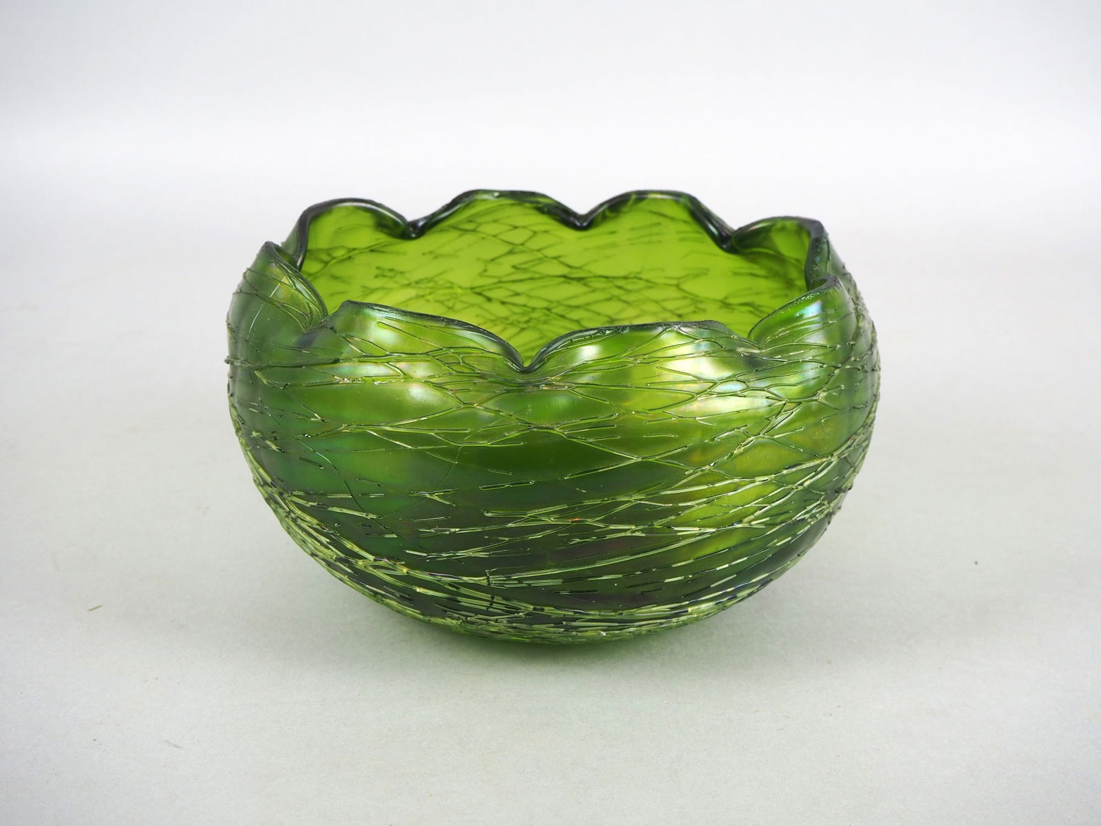Glass bowl "Loetz", around 1900.: Glass bowl "Loetz", around 1900.Body in pumpkin shape made of thick clear glass with braided meltings colored in green tones, slightly iridescent. Wavy indented bowl mouth, small stand with cut demoli