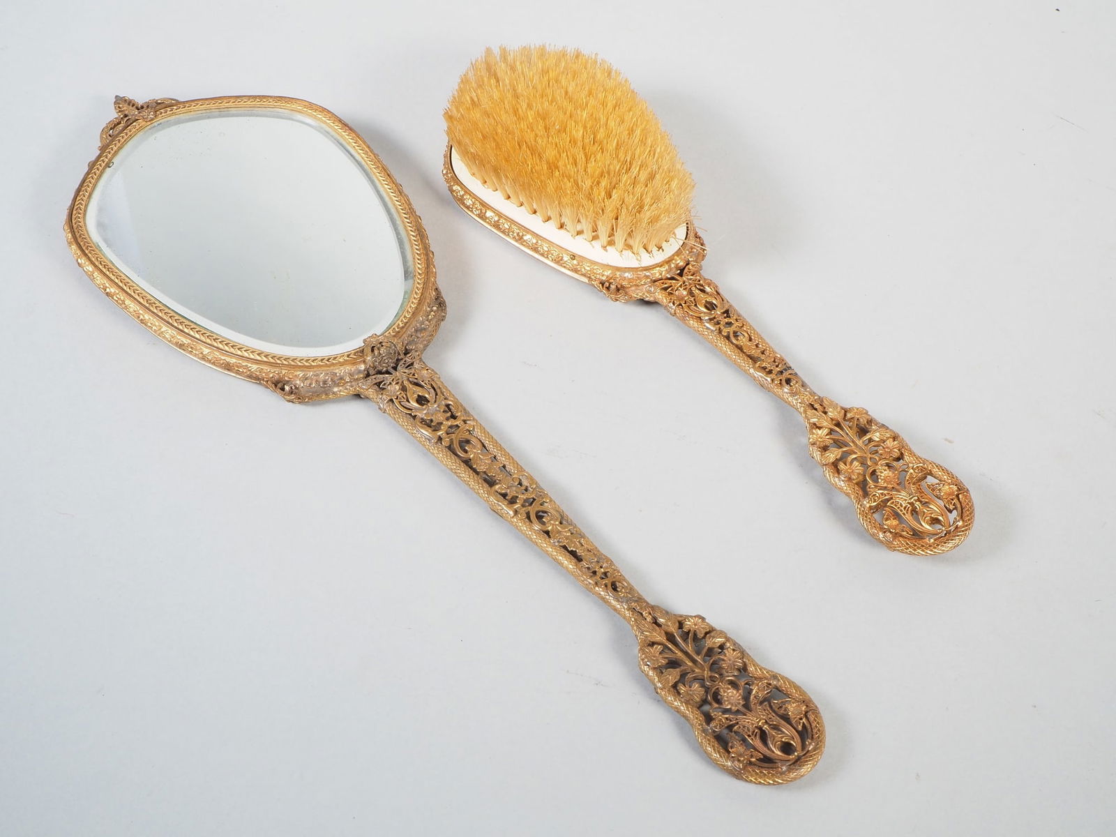 Hand mirror and brush, around 1880: Hand mirror and brush, around 1880 Made of bronze, gilded, very delicately open-worked. Richly decorated with floral motifs in relief. Oval, cut mirror glass. Signs of age and wear, very decorative. M