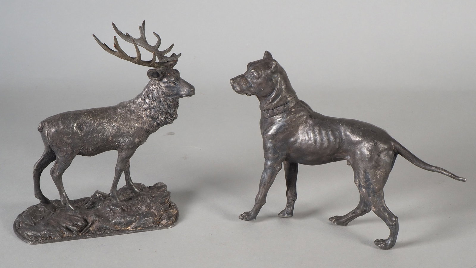 Two table sculptures, around 1900: Two table sculptures, around 1900 Both made of metal, probably pewter. A stag with large antlers, on a rectangular stand. Height 16.5 cm, width 14 cm, and a dog, naturalistically moulded, with maker's