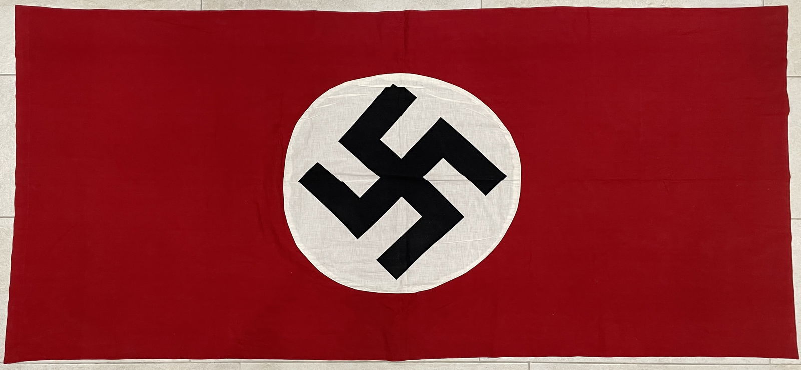 Third Reich: NS house flag - 233 x 106 cm: Third Reich: NS house flag - 233 x 106 cmNational Socialist house flag from the time of the 3rd Reich. White circle with swastika sewn on both sides on red flag cloth. One side can be looped through.