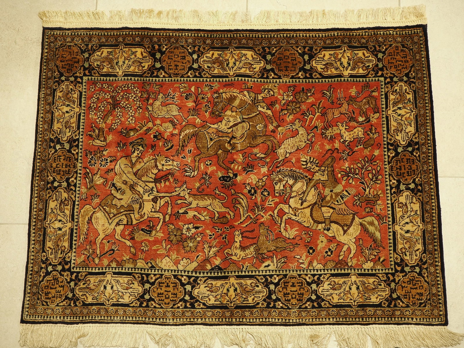 Ghom silk carpet with hunting scene, 107 x 80 cm: Ghom silk carpet with hunting scene, 107 x 80 cmHand-knotted fine Persian carpet made of 100% pure natural silk on silk, depicting a dynamic hunting motif (Shikargah), three horsemen in traditional dr