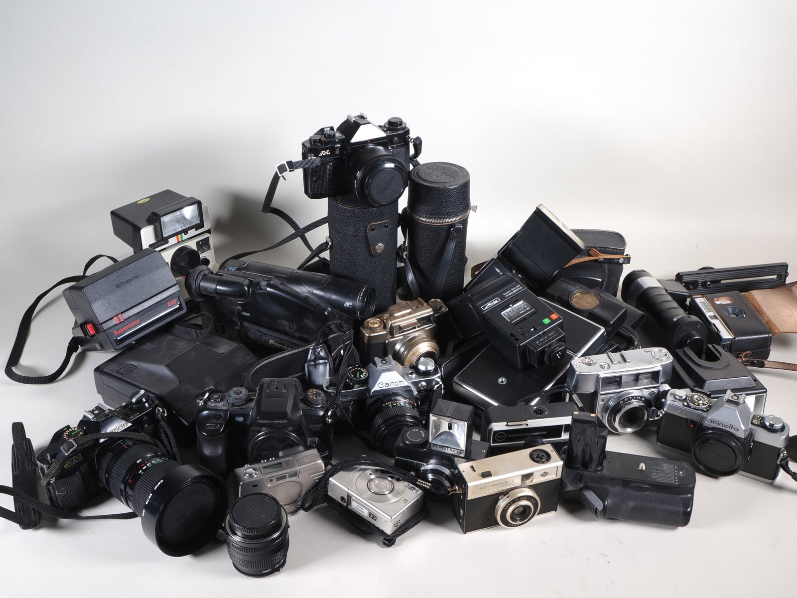 Collection of vintage cameras, lenses and accessories: Collection of vintage cameras, lenses and accessoriesBox full of old vintage cameras and accessories, including Minolta XG1; Porst Lucky; Canon Ixusi II; Canon A-1; Polaroid Polatronic 1000; Canon AE-