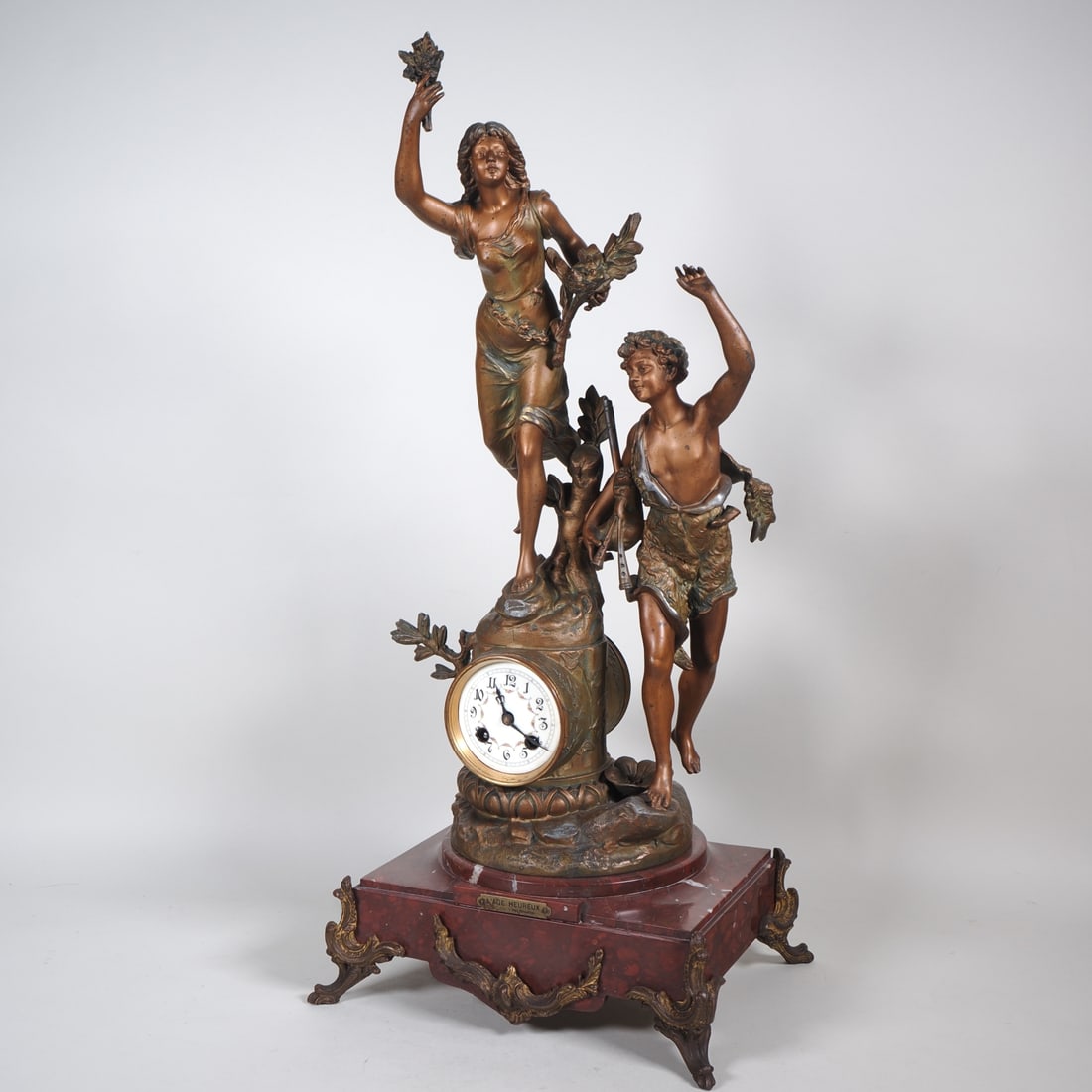 Large figurine clock "Lenzkirch" circa 1880: Large figurine clock "Lenzkirch" circa 1880Heavy rectangular base made of red marble with four feet, curved shape decorated with rocaille motifs. Clockwork case attached to the base with two large fig