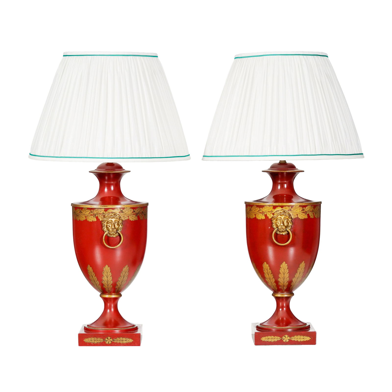 Paire de lampes de style Restauration, XXe s., en forme d'urne en tôle rouge, flanquée de : Paire de lampes de style Restauration, XXe s., en forme d'urne en tôle rouge, flanquée de mufles de lion, abat-jour en soierie plissée blanche, h. 39 cm Provenance: Hôtel Victoria