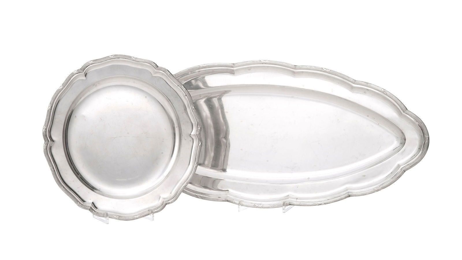 Ensemble d'1 plat ovale et 1 plat ronds polylobés en argent, Autriche-Hongrie, à déco: Ensemble d'1 plat ovale et 1 plat ronds polylobés en argent, Autriche-Hongrie, à décor de rubans croisés, diam. 33 cm, long. 70,5 cm, 2440g Conditionmicrorayures d'usage