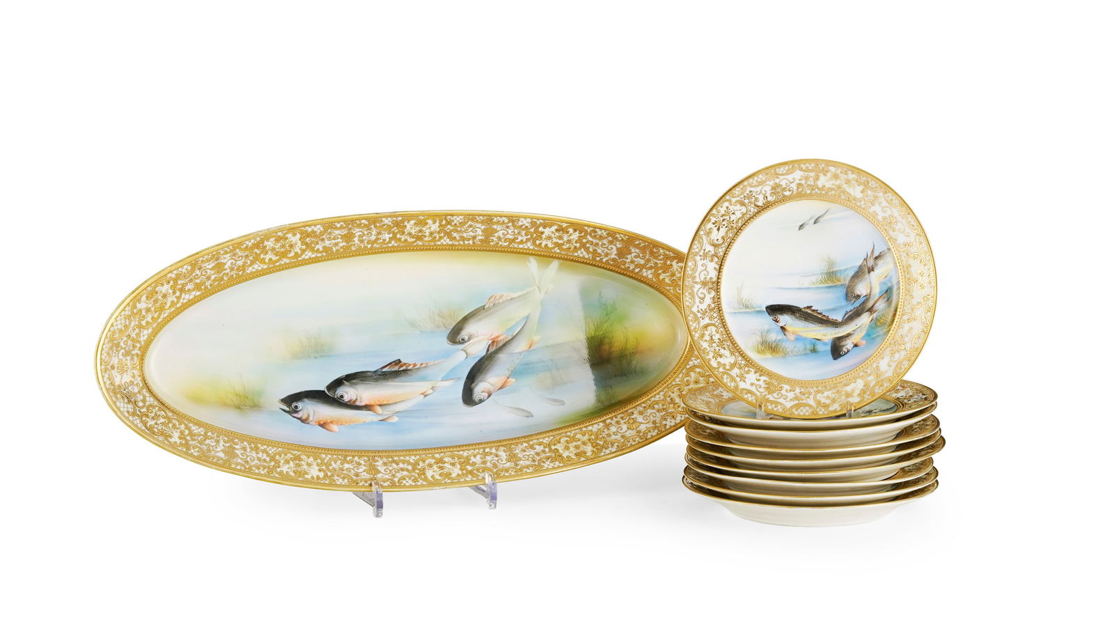 Ensemble de 9 assiettes et 1 plat ovale en porcelaine, marque Nippon, à décor polychrome d: Ensemble de 9 assiettes et 1 plat ovale en porcelaine, marque Nippon, à décor polychrome de poissons et marli à décor de volutes feuillagées et treillage Condition éclat