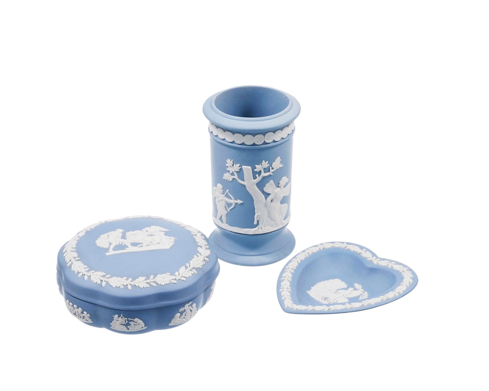 Ensemble de 3 pièces en biscuit bleu de Wedgwood, à décor blanc à l'antique, com: Ensemble de 3 pièces en biscuit bleu de Wedgwood, à décor blanc à l'antique, comprenant: 1 pot à crayons, 1 coupelle coeur et 1 boîte ronde polylobée 