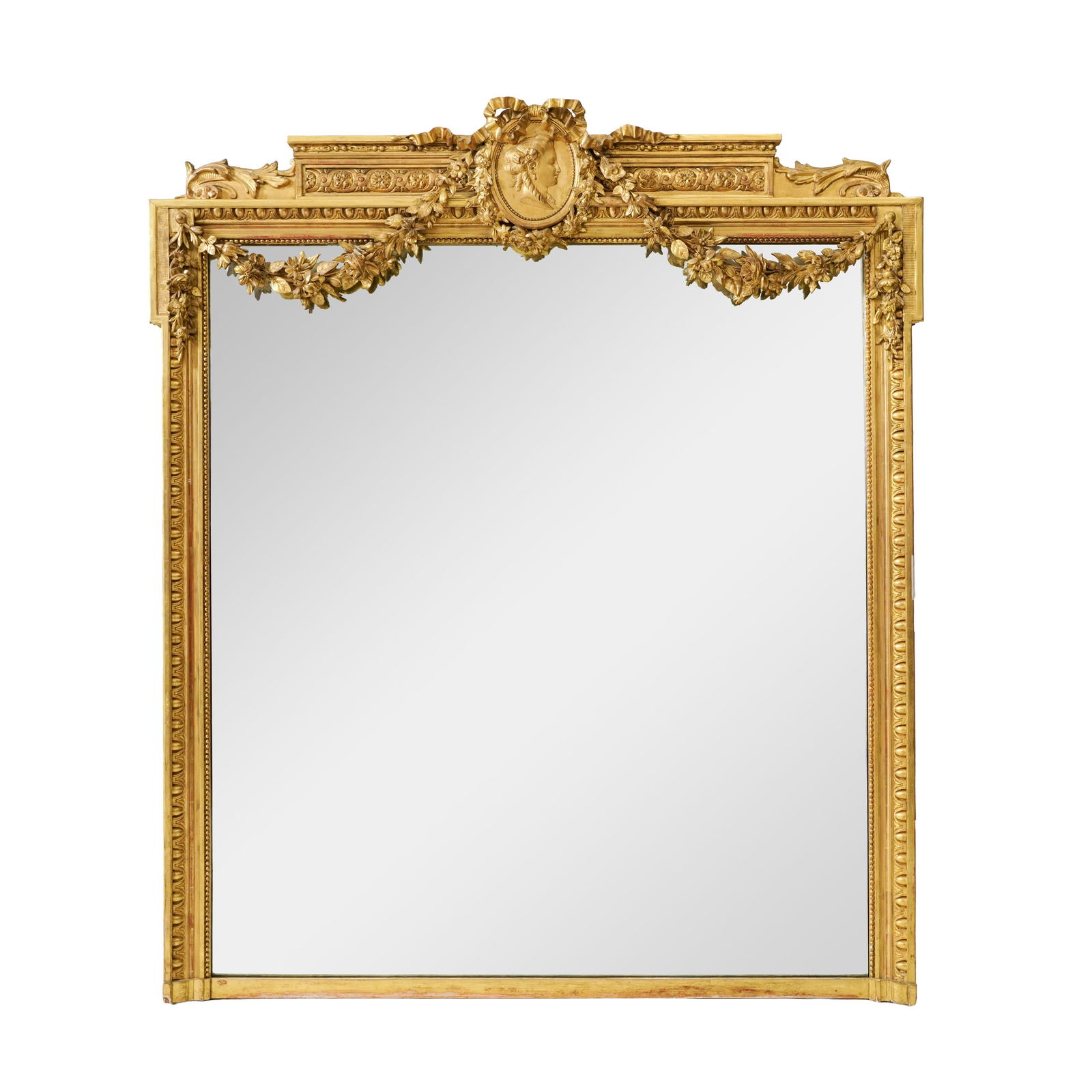 Miroir de style Louis XVI, fin du XIXe s., en bois et stuc doré à décor de godrons, g: Miroir de style Louis XVI, fin du XIXe s., en bois et stuc doré à décor de godrons, guirlandes de fleurs, entrelacs, fronton flanqué d'un médaillon d'un portrait de femme de