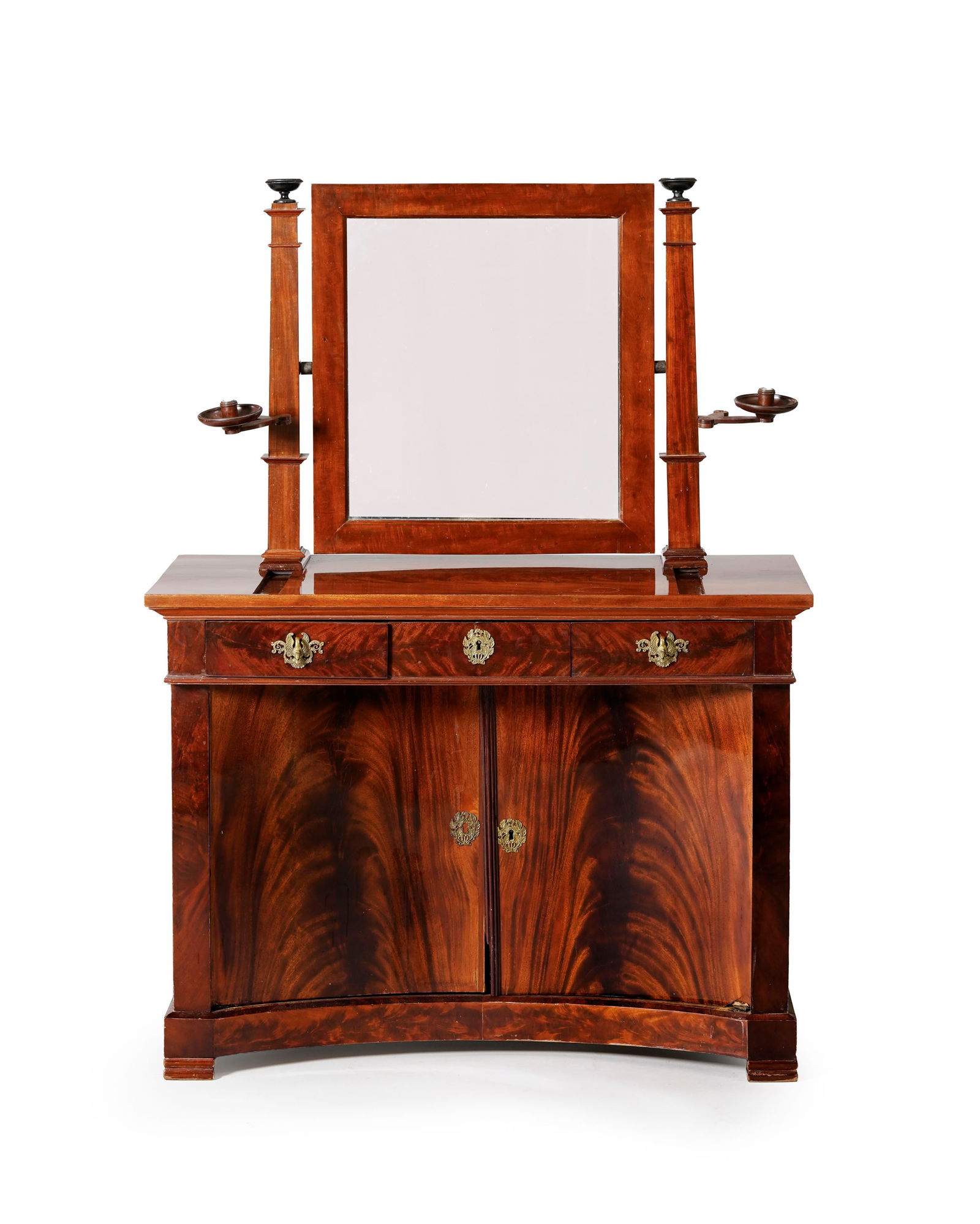 Coiffeuse de style Empire, XIXe s., en placage d'acajou flammé, à façade incurvé: Coiffeuse de style Empire, XIXe s., en placage d'acajou flammé, à façade incurvée ouvrant par deux vantaux et trois tiroirs, plateau surmonté d'un miroir basculant et