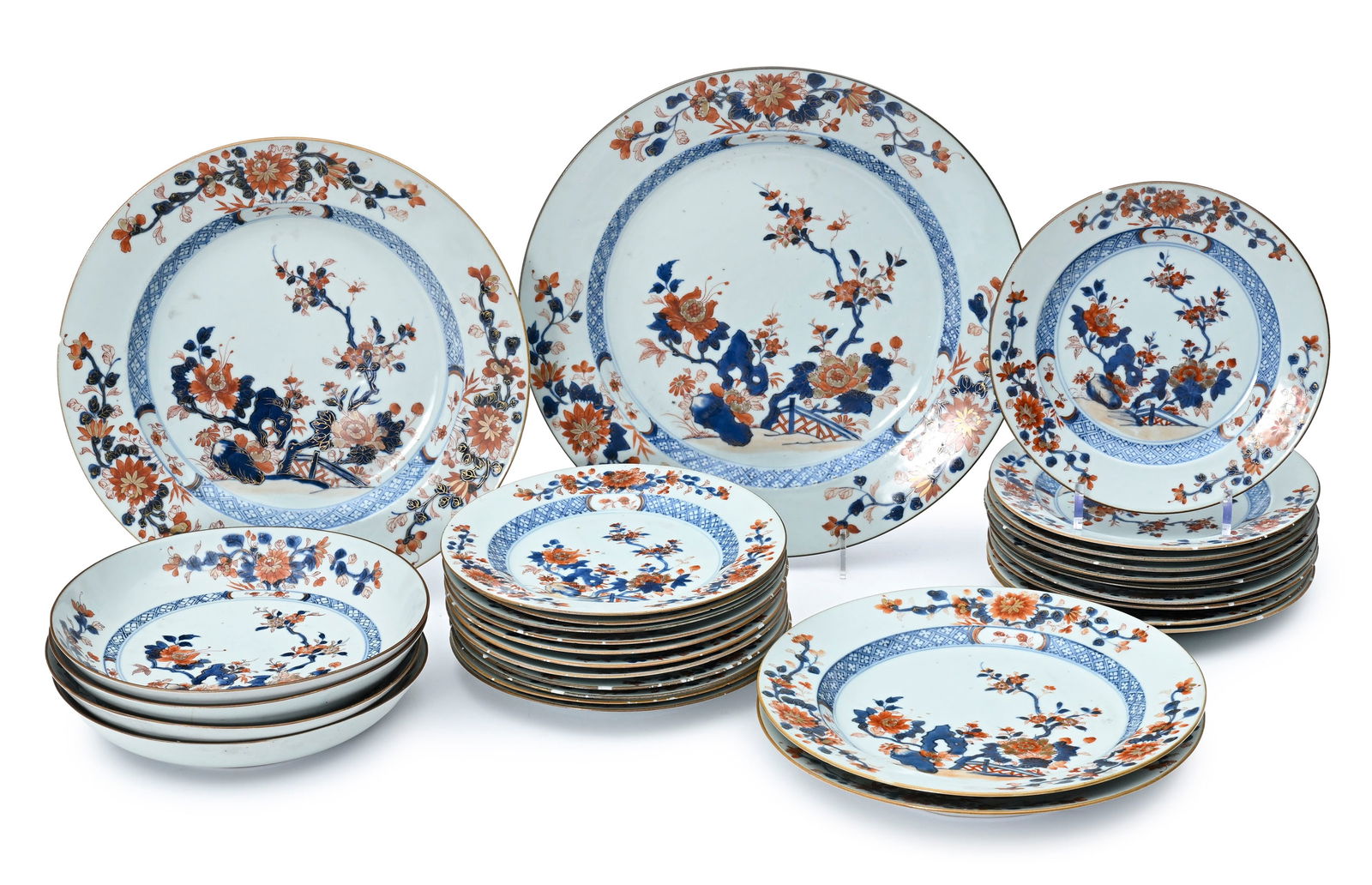 Ensemble de 10 assiettes et 2 plats en porcelaine Imari, Chine, dynastie Qing: décor de fleurs : Ensemble de 10 assiettes et 2 plats en porcelaine Imari, Chine, dynastie Qing: décor de fleurs et rochers, diam. 23 cm (assiettes), diam. 28,5 et 35,5 cm (plats) (éclats). On joint 11