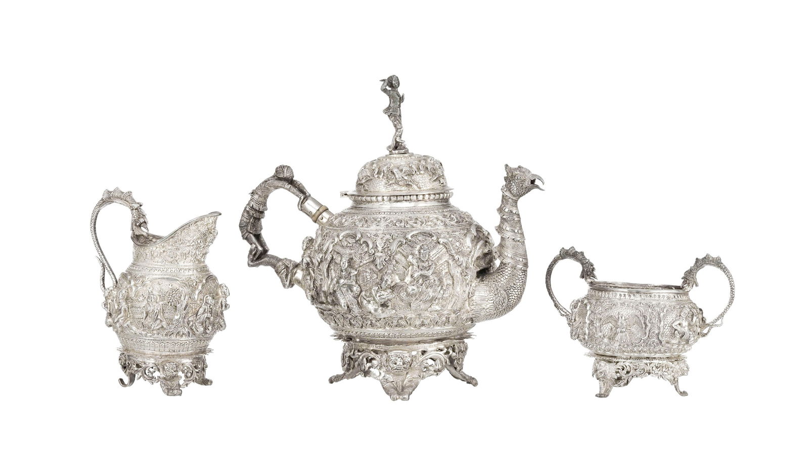 Service à thé en argent, comprenant 1 théière, 1 crémier et 1 sucrier, Birm: Service à thé en argent, comprenant 1 théière, 1 crémier et 1 sucrier, Birmanie, XIX-XXe s., riche décor en relief de multiples personnages, animaux, créatures