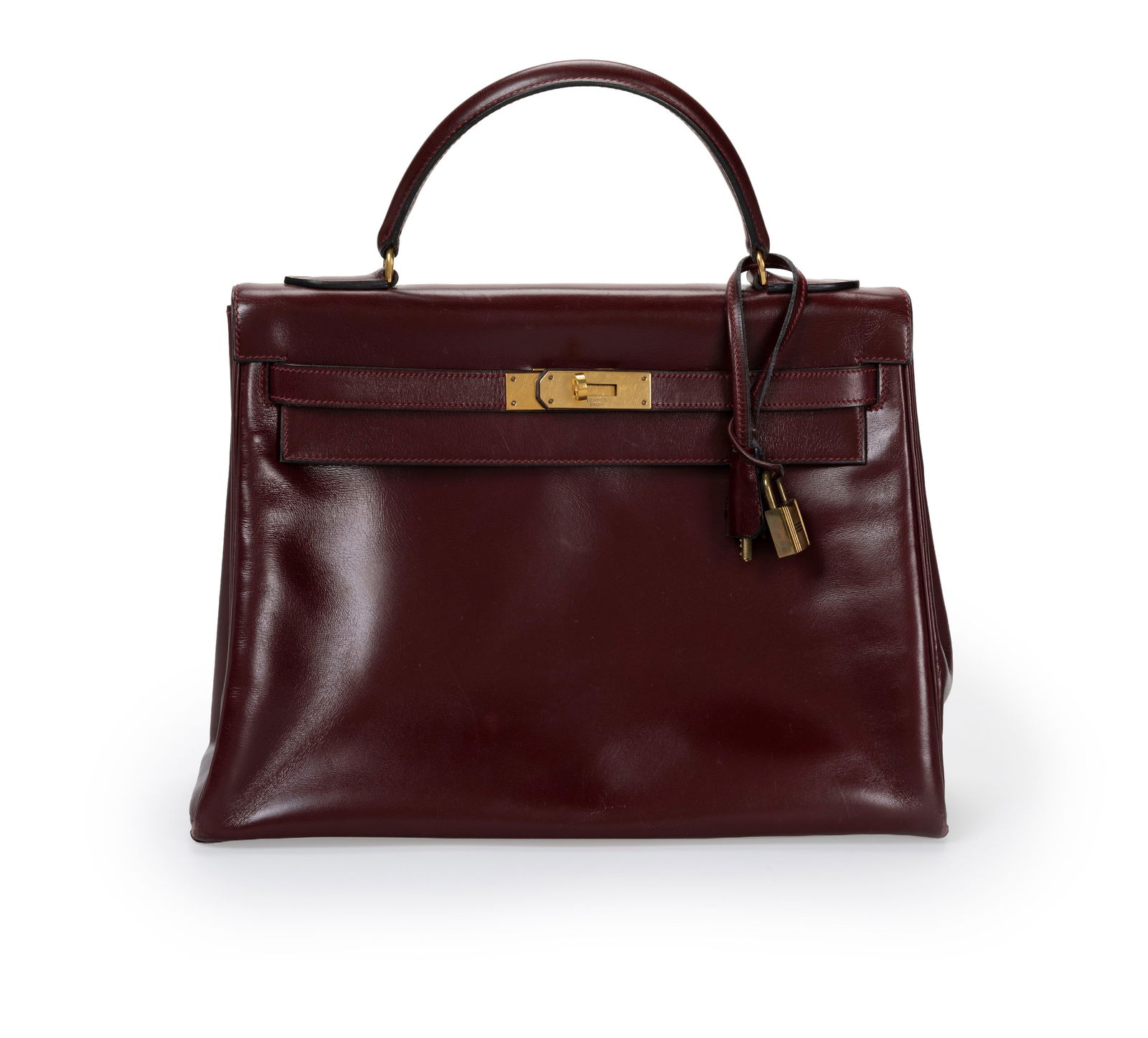 Hermès, sac Kelly 32 Retourné en cuir de box bordeaux, année 1974, bouclerie plaqu: Hermès, sac Kelly 32 Retourné en cuir de box bordeaux, année 1974, bouclerie plaquée or, tirette, clochette, 2 clefs et cadenas, 23x32 cm ConditionBon état de conservation