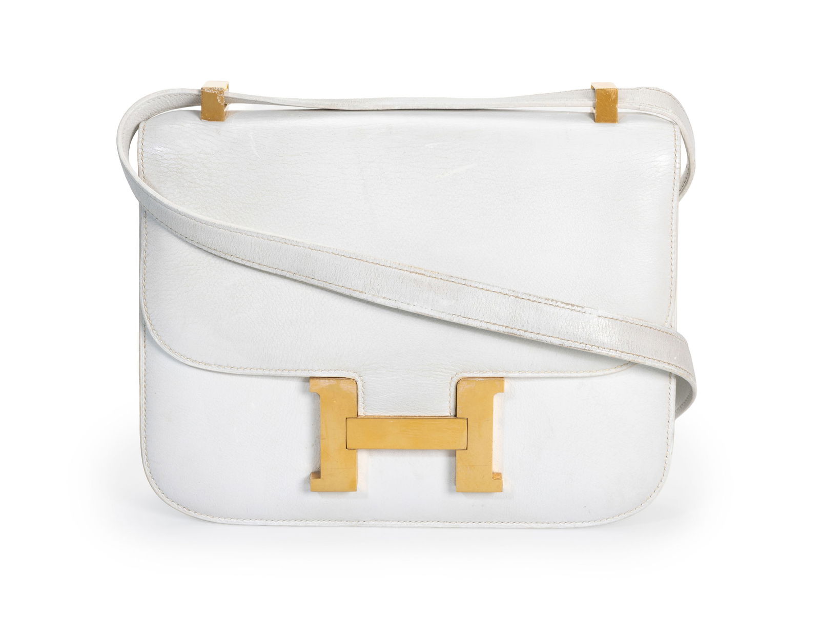 Hermès, sac Constance en cuir blanc, année 1975, bouclerie plaquée or, bandouliè: Hermès, sac Constance en cuir blanc, année 1975, bouclerie plaquée or, bandoulière portée épaule, 17x23 cm Condition A remettre en état. Ce sac est en mauvais é