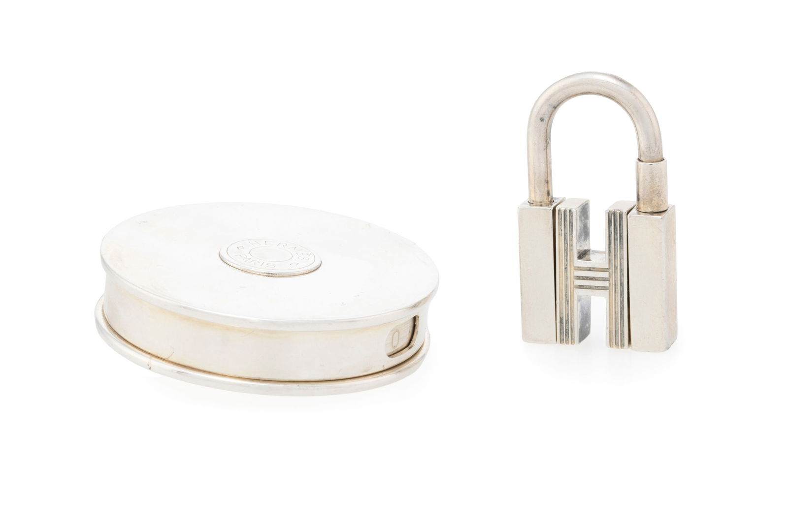 Hermès, cadenas pendentif et boîte à pilule en métal couleur argent, boîte,: Hermès, cadenas pendentif et boîte à pilule en métal couleur argent, boîte, h. 4 cm et diam. 5 cm ConditionBon état de conservation Beaucoup de micro rayures d'usure 