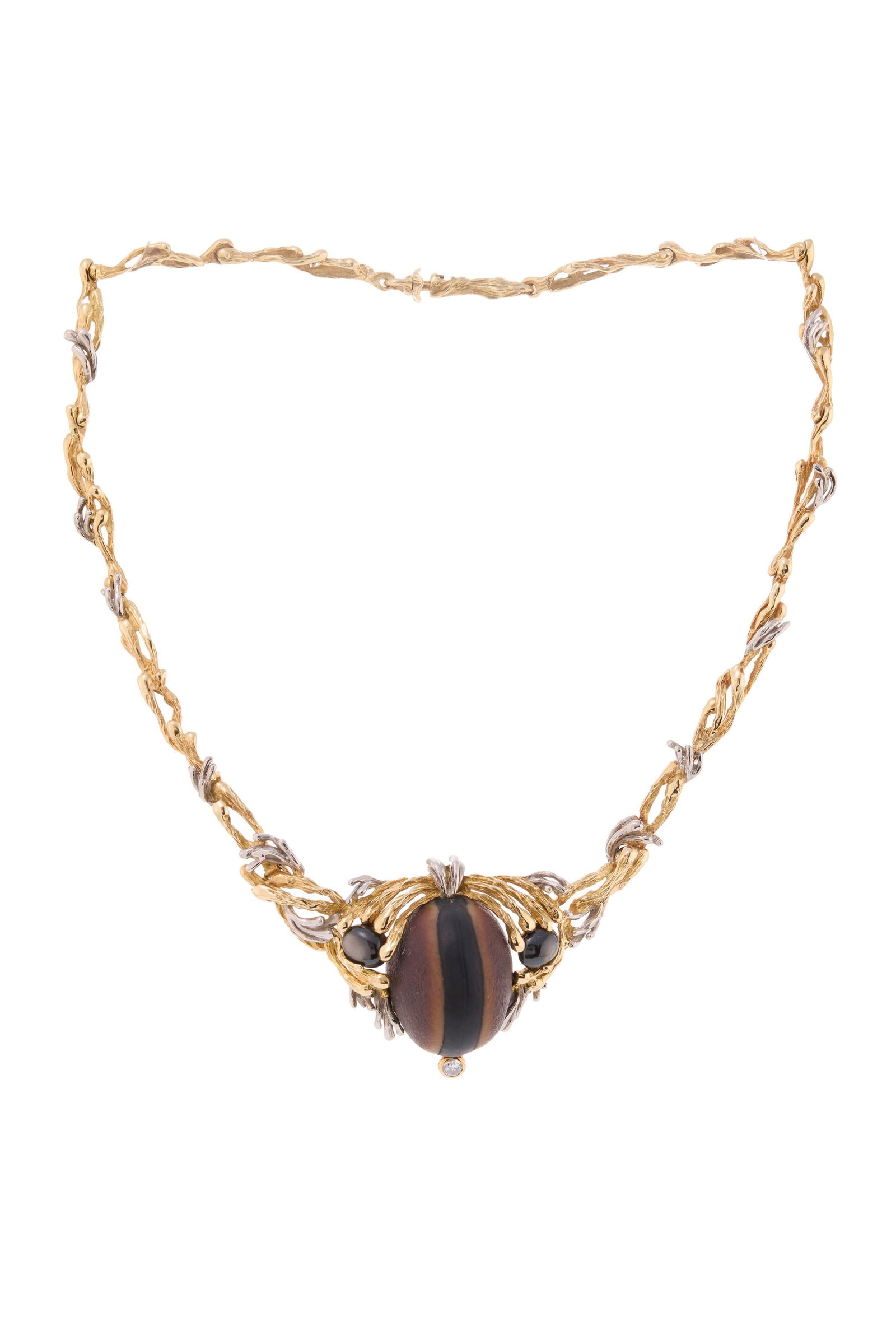 Gilbert Albert, collier 2 ors 750 stylisant un décor végétal enserrant une graine : Gilbert Albert, collier 2 ors 750 stylisant un décor végétal enserrant une graine œil de bœuf encadrée de saphirs étoilés noirs et d'un diamant taille brillant,