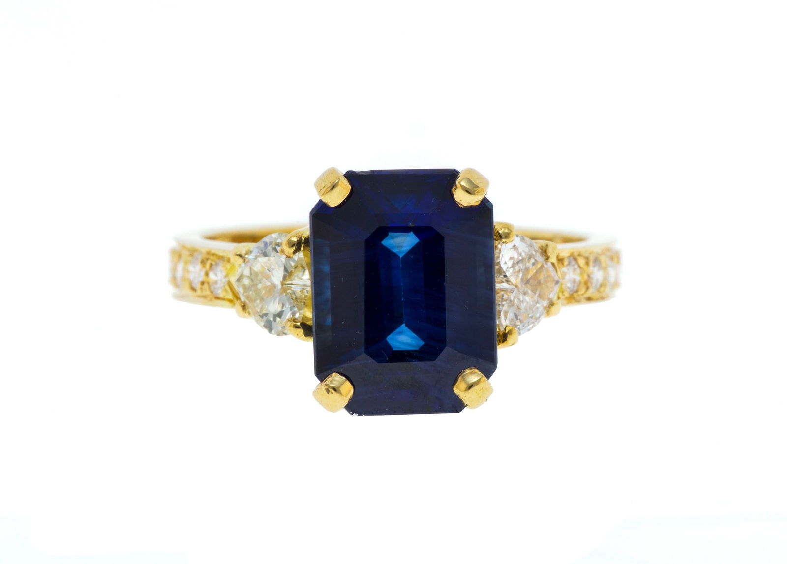 Bague or 750 sertie d'un saphir taille émeraude épaulée de diamants taille cœur : Bague or 750 sertie d'un saphir taille émeraude épaulée de diamants taille cœur et brillant, doigt 53-13 ConditionMonture: Bon à très bon état, présence de