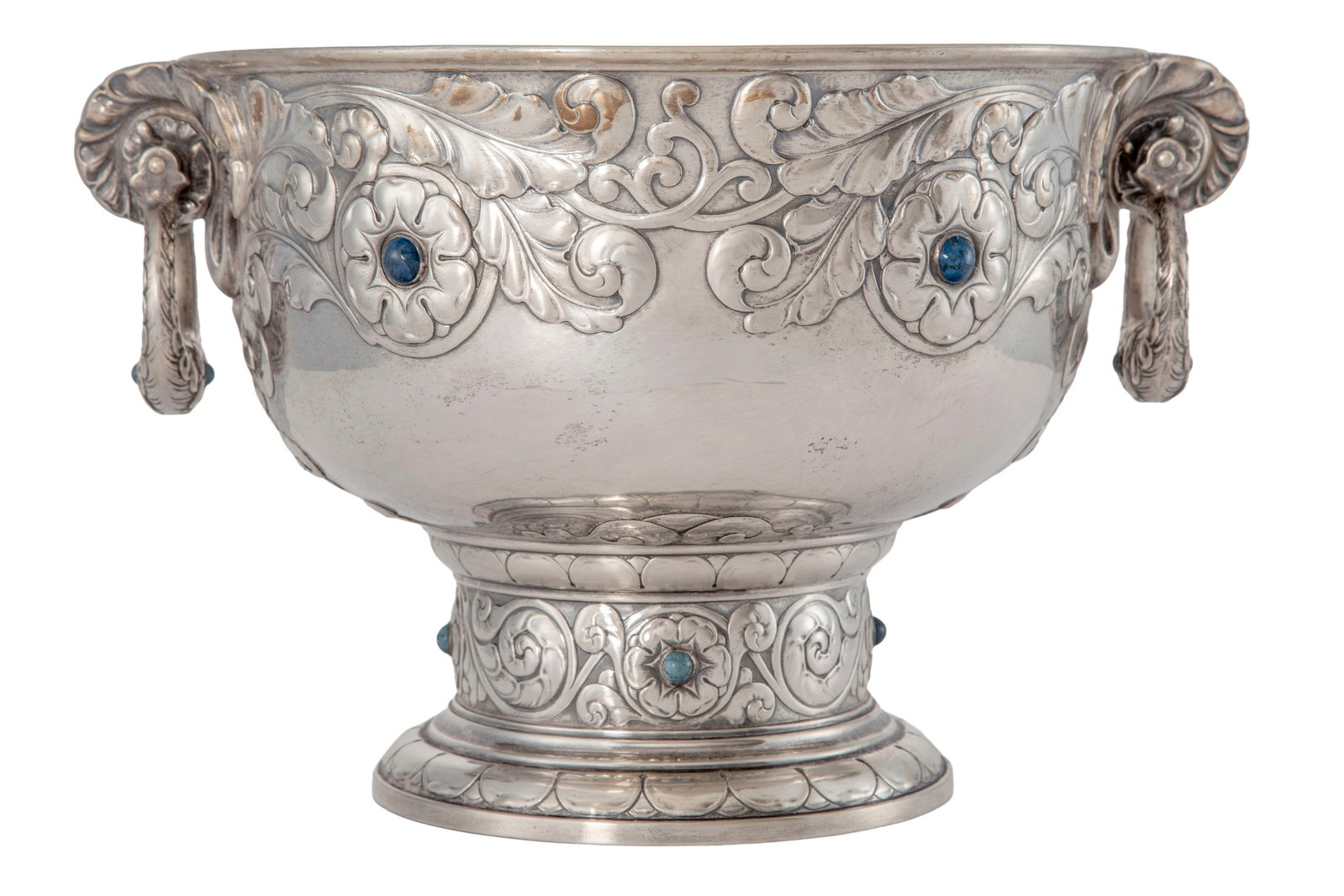 Coupe à anses sur piédouche en argent, par K C Hermann, Copenhague, 1910, à déco: Coupe à anses sur piédouche en argent, par K C Hermann, Copenhague, 1910, à décor repoussé de fleurs et feuillage avec cabochons bleus, les anses mobiles, diam. 30,5 cm, h. 23