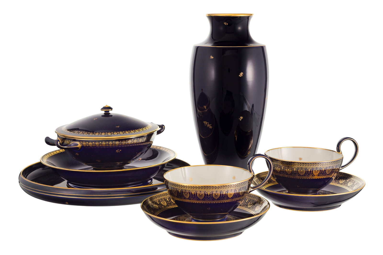 Sèvres. Ensemble de 5 pièces en porcelaine de Sèvres, années 1955-58, à d&#: Sèvres. Ensemble de 5 pièces en porcelaine de Sèvres, années 1955-58, à décor or sur fond bleu cobalt: 2 tasses et soucoupes, 1 bouillon couvert, 1 vase et 1
