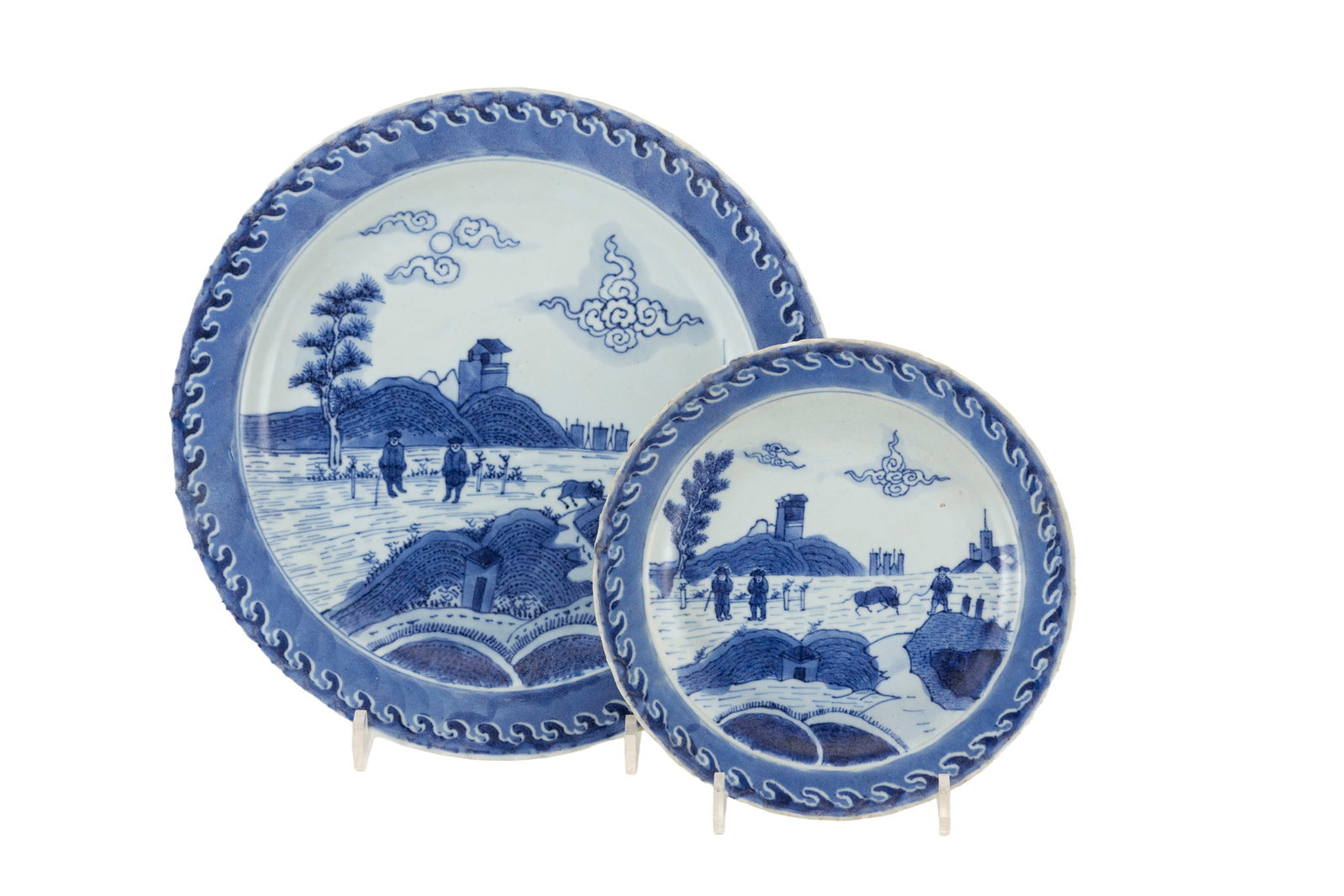 Assiette et plat en porcelaine, Chine, ca 1690, provenant du "Vung Tau Cargo", décor en bleu de: Assiette et plat en porcelaine, Chine, ca 1690, provenant du "Vung Tau Cargo", décor en bleu de personnages dans un paysage, marli orné de vagues, diam. 20 cm et diam. 29,5 cm (restaurations