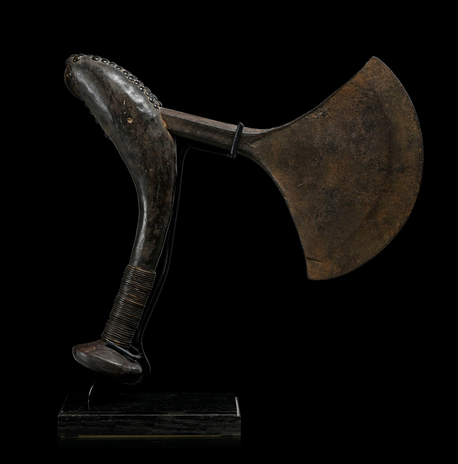 Hache ibia Teke, manche recourbé en bois à patine brun foncé, orné de clous de t: Hache ibia Teke, manche recourbé en bois à patine brun foncé, orné de clous de tapissier en partie supérieure, prise gainée de fil de laiton, lame en fer