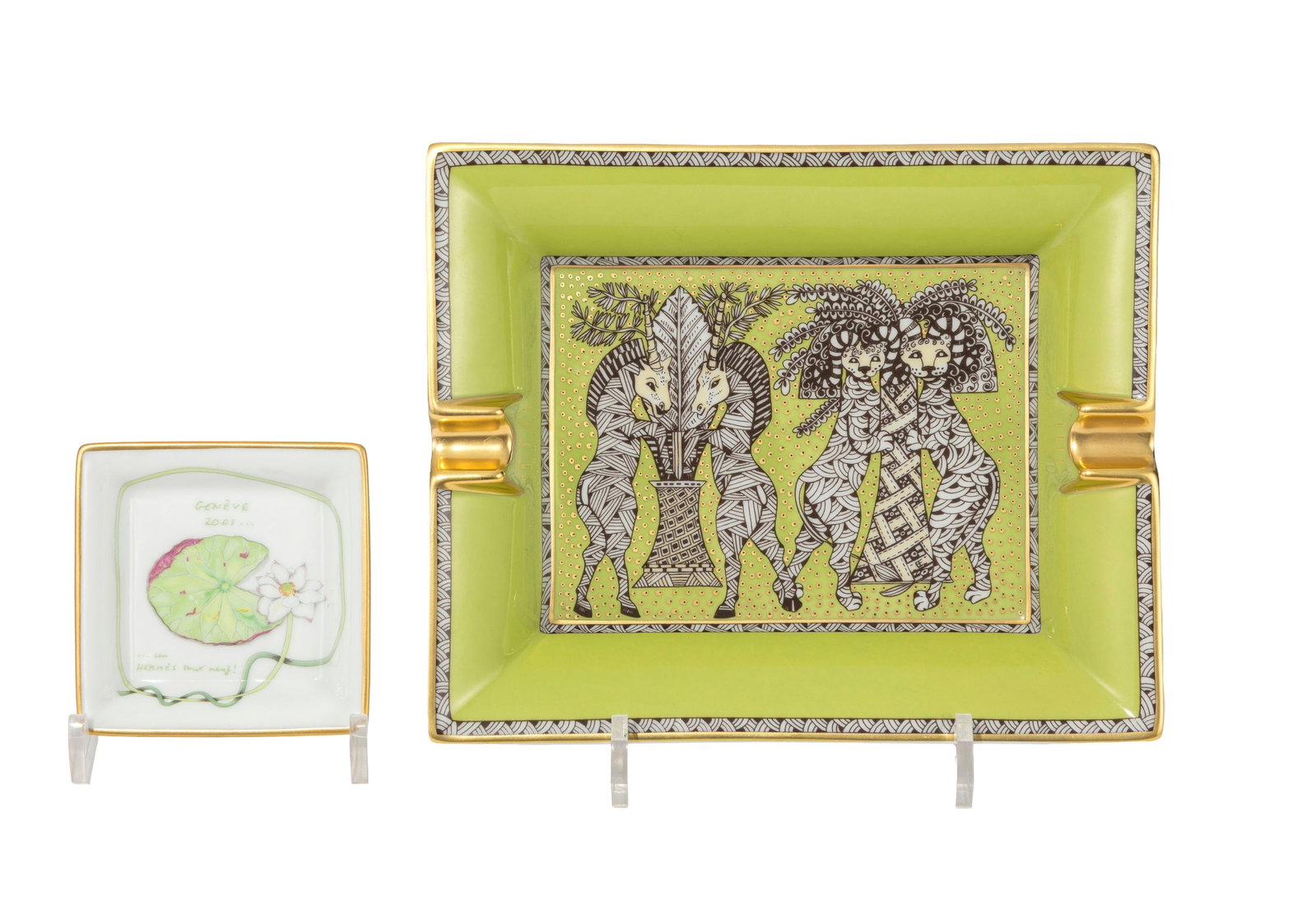 HERMÈS. Ensemble de 2 vide-poches cendriers en porcelaine, Made in France, à décor po: HERMÈS. Ensemble de 2 vide-poches cendriers en porcelaine, Made in France, à décor polychrome collection Africa pour l'un et "Genève 2001... un Hermès tout neuf" avec