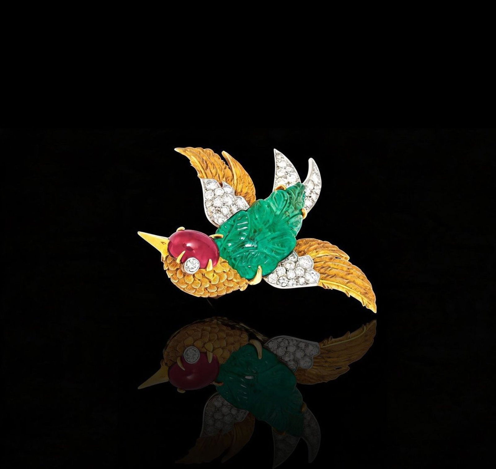 Cartier, broche oiseau circa 1950 or texturé stylisant le plumage et platine ornée d'une &: Cartier, broche oiseau circa 1950 or texturé stylisant le plumage et platine ornée d'une émeraude gravée, d'un cabochon de rubis ainsi que de diamants taille brillant et 8/8, sign&