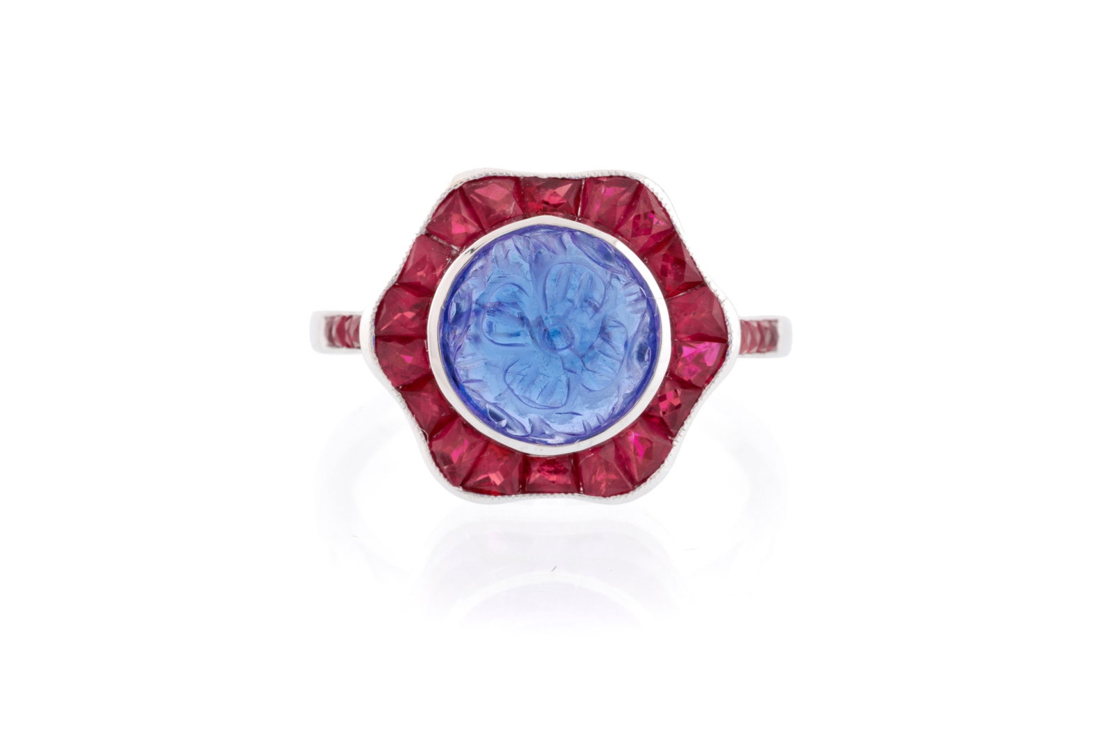 Bague or 750 sertie d'une tanzanite gravée d'un motif floral entourée de rubis calibré: Bague or 750 sertie d'une tanzanite gravée d'un motif floral entourée de rubis calibrés, doigt 54-14 Condition Très bon état de conservation général. Quelques