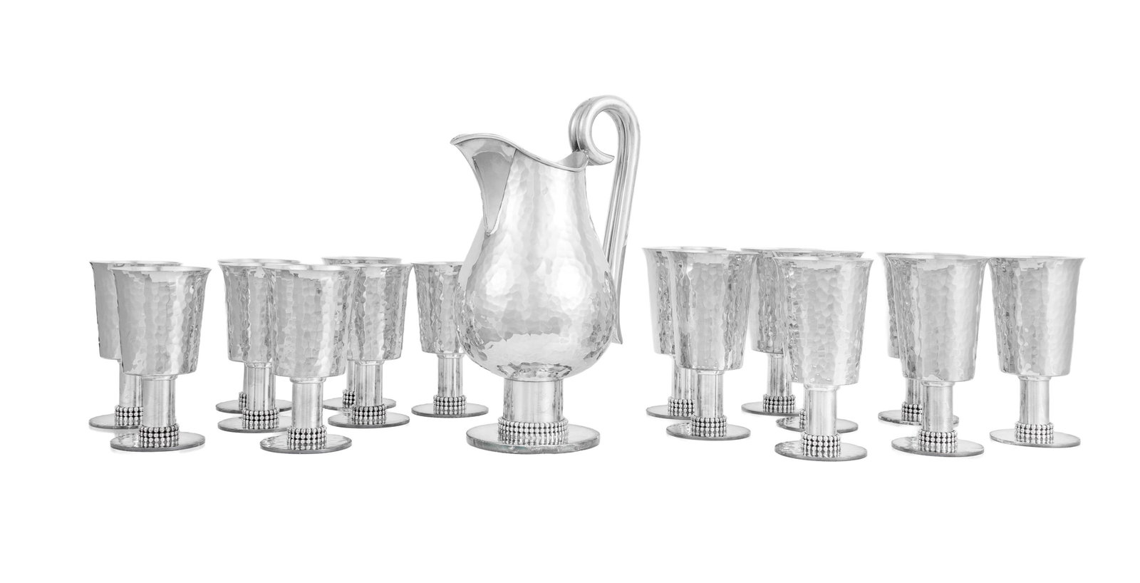 Jean Després (1889-1980). Service de 16 verres (8 à eau et 8 à vin) et 1 pichet en m&: Jean Després (1889-1980). Service de 16 verres (8 à eau et 8 à vin) et 1 pichet en métal argenté martelé, circa 1950, signés sous les bases, h. 12,5 et 14 cm Mus