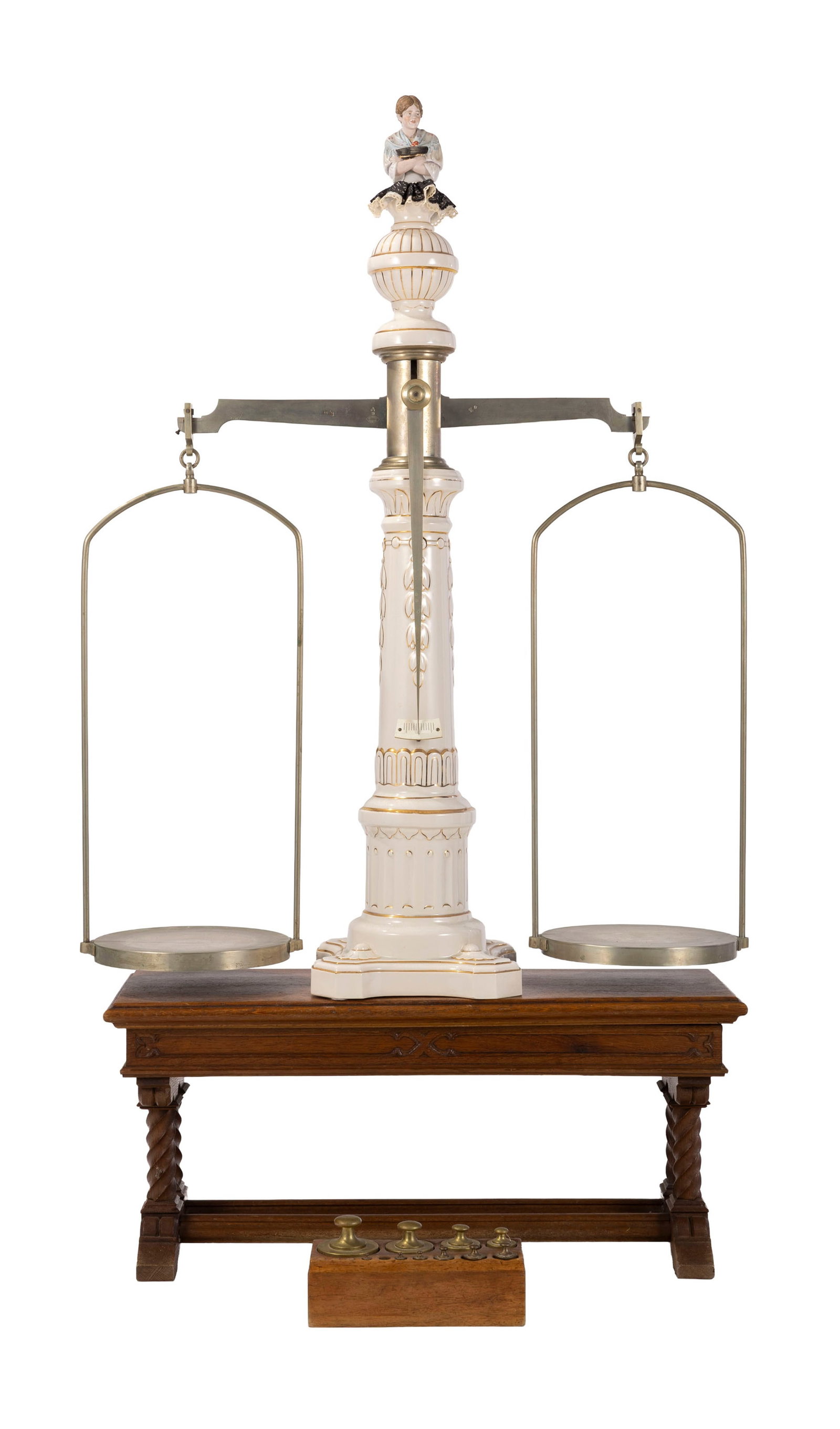 Balance trébuchet à colonne par Gaudenzi à Genève, en acier et porcelaine, avec : Balance trébuchet à colonne par Gaudenzi à Genève, en acier et porcelaine, avec une sellette en bois, une barquette en bois contenant dix poids, et une statuette sommitale en