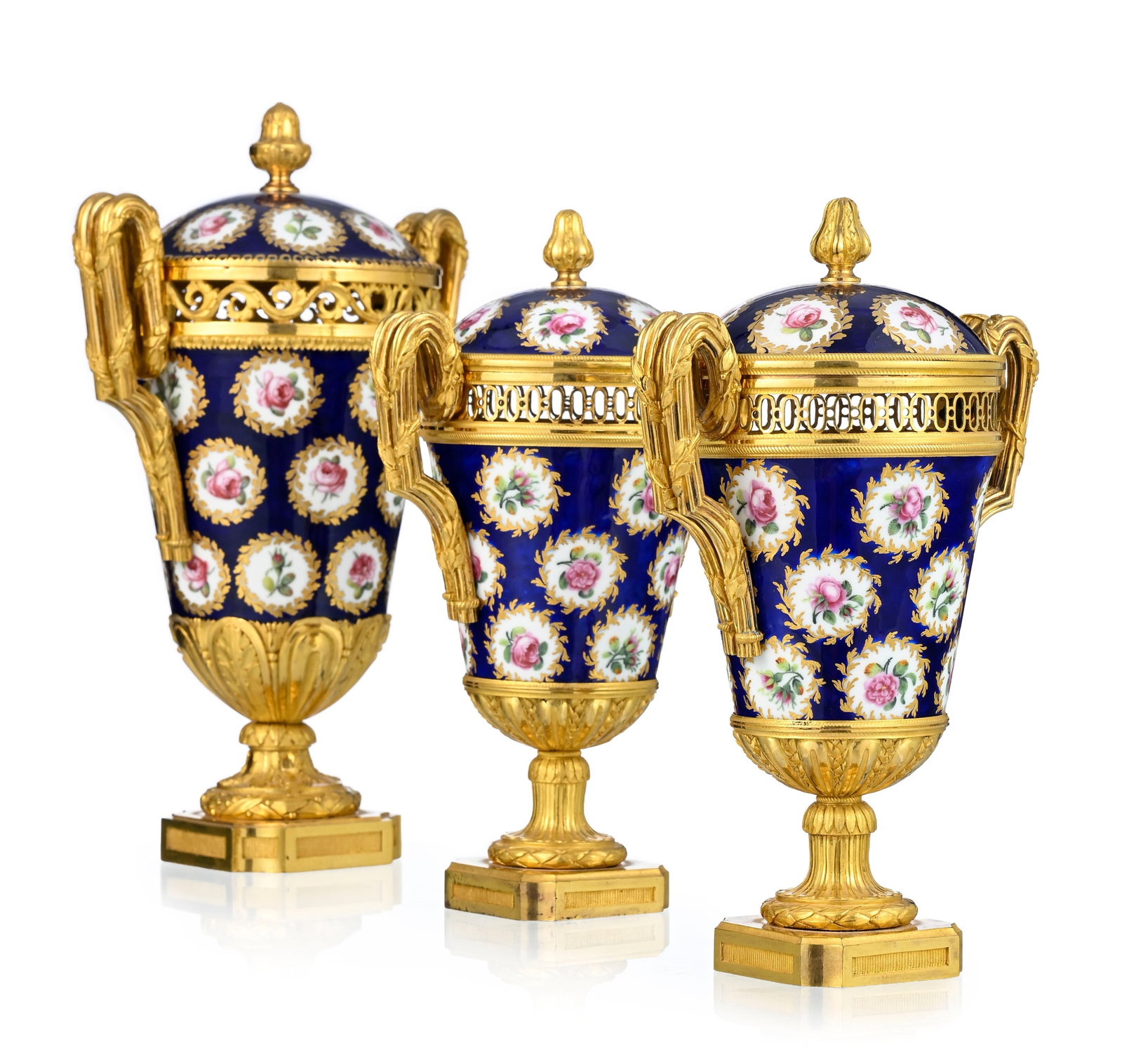 Garniture composée de trois pot-pourris, fin d'époque Louis XVI, en porcelaine de Sèv: Garniture composée de trois pot-pourris, fin d'époque Louis XVI, en porcelaine de Sèvres à décor polychrome d'un semi de roses dans des cartouches feuillagés or sur fond 