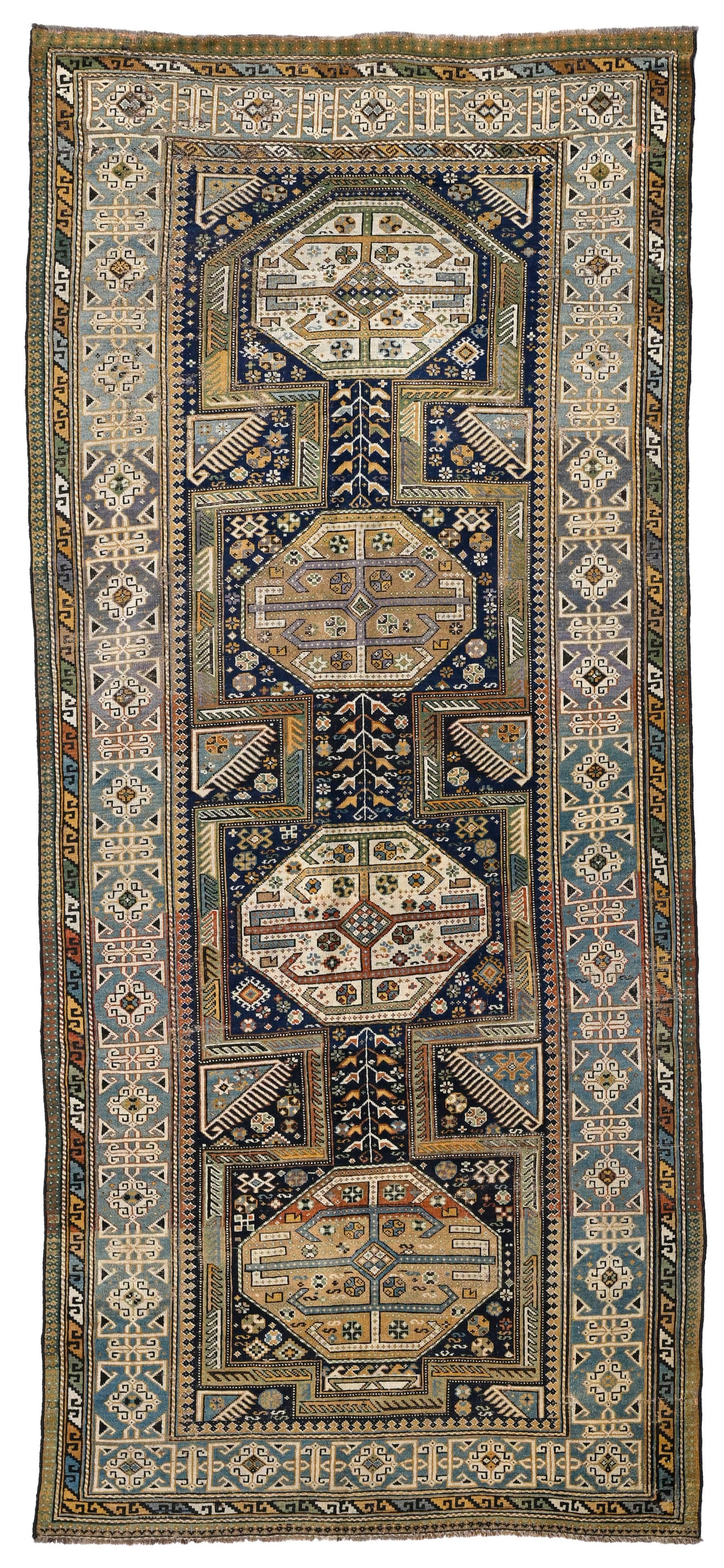 Tapis Daghestan, Caucase, 1er tiers du XXe s., orné d'une rangée centrale d'octogones beig: Tapis Daghestan, Caucase, 1er tiers du XXe s., orné d'une rangée centrale d'octogones beiges et bruns sur fond bleu parsemé de motifs stylisés, bordure bleue à motifs