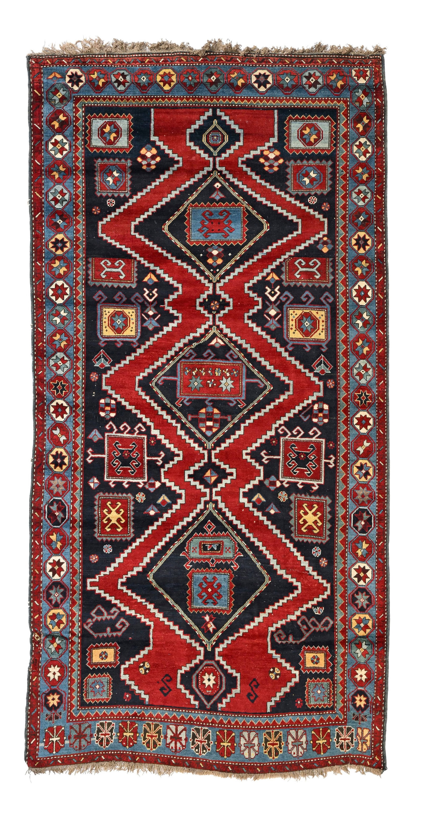 Tapis Kazakh, Caucase, 1er tiers du XXe s., orné d'une rangée centrale de losanges sur fon: Tapis Kazakh, Caucase, 1er tiers du XXe s., orné d'une rangée centrale de losanges sur fond rouge et bleu marine parsemé de motifs géométriques, bordure bleu ciel
