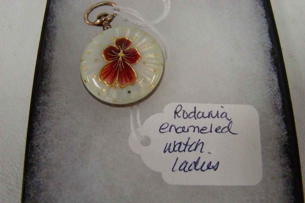 An enameled watch pendant with white ground and re: and red flower with gold accents, marked Rodania anti- magnetic