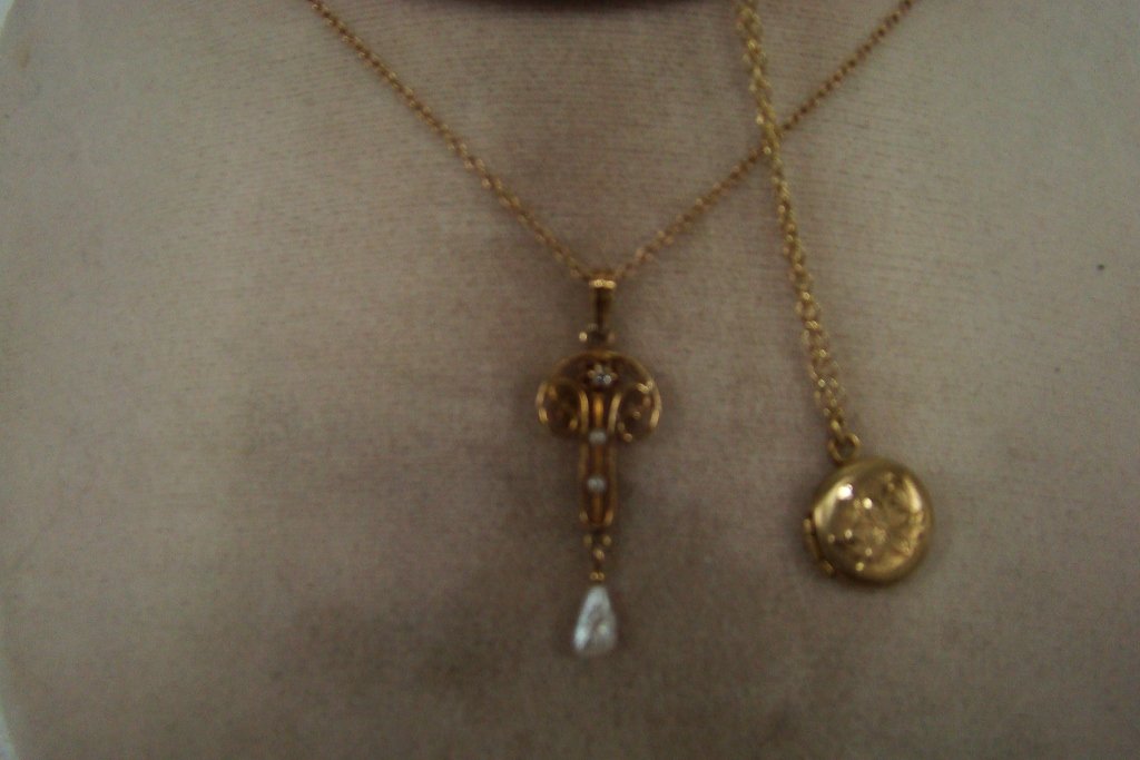 A yellow gold lavaliere marked 10kt with diamond, : 2 seed pearls and 1 fresh water pearl and a yellow gold baby's locket, marked 10kt