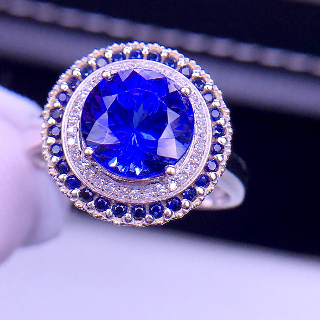 18K White Gold 3 CT Tanzanite & Diamond Ring: Ref:2465 Gold Content:18K White Gold Weight of Item:3.5grams Ring Size:7.25US Main Gemstone:Tanzanite Number of stones:1 Shape:Round Carat Weight:3ct Clarity Grade:VS2 Color:Blue Cut Grade:G Adjacent 
