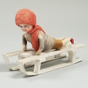 Antique German Heubach bisque head & cotton boy laying on sled - 4 1/2" long