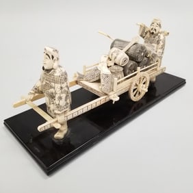 Lg ornate carved & decorated Chinese bone sculpture of 2 men w/ wagon & fish, etc mounted on lacquer