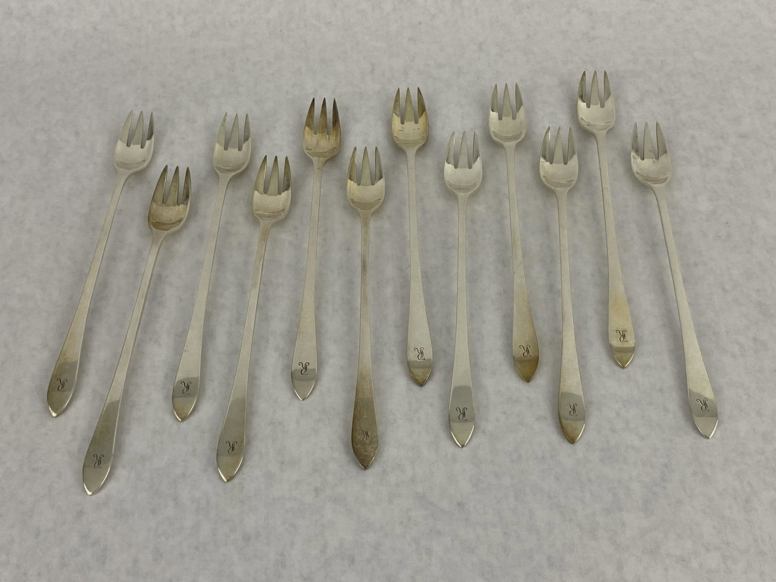 12 Tiffany & Co Sterling Silver Faneuil Oyster Forks: Set of 12 Sterling Silver 3-Tine Oyster Forks in the Faneuil Pattern. Marked "M Tiffany & Co. Sterling" and measuring 6-1/8". Each Fork is monogrammed with "R" and weighs 27g. Total weight is 324g.