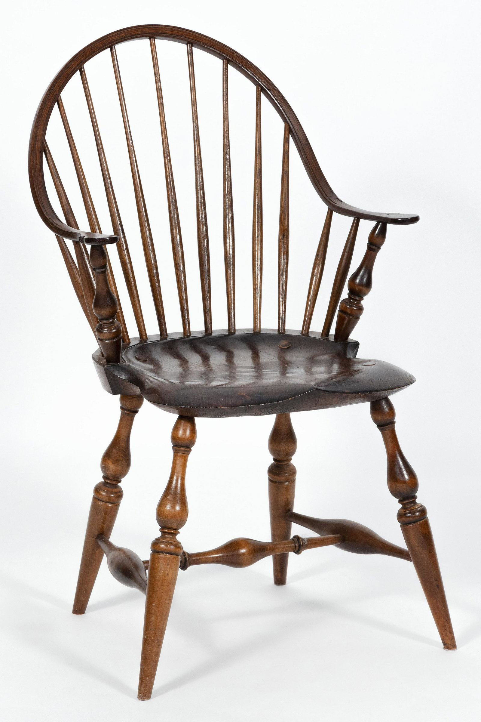 WINDSOR-STYLE CONTINUOUS BOWBACK ARMCHAIR In mixed: WINDSOR-STYLE CONTINUOUS BOWBACK ARMCHAIR 20th Century In mixed hardwoods, under a reddish-brown stain. Marked "WCW" on underside of seat, possibly for Warren Chair Works of Warren, Rhode Island. Back