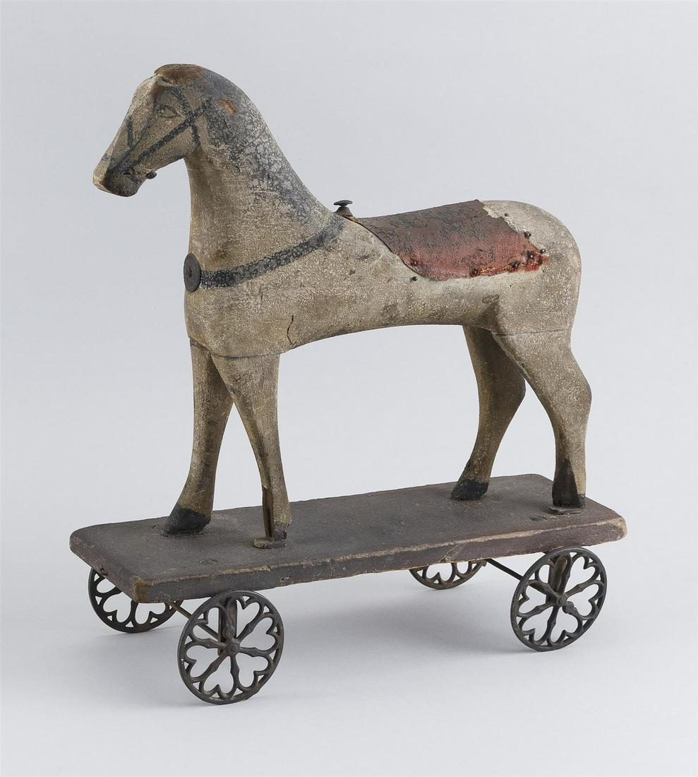 HORSE PULL TOY Carved wooden body under original paint.: HORSE PULL TOY 19th Century Carved wooden body under original paint. Applied leather saddle. Mounted on a wooden base with metal wheels. Height 13". Length 13.5".