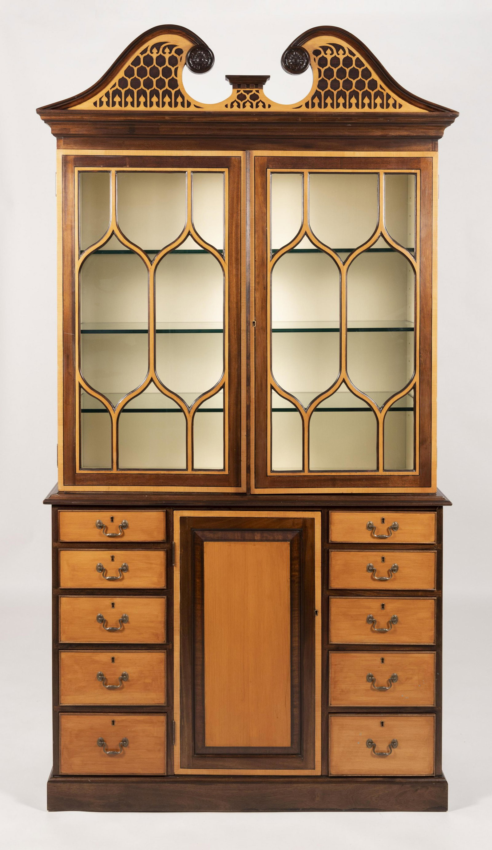 THE FEDERALIST CO. TWO-PART CABINET In maple veneer,: THE FEDERALIST CO. TWO-PART CABINET Contemporary In maple veneer, mahogany veneer and other hardwood veneers. Upper case with broken arch pediment over two glass doors. Lower case with a central panel