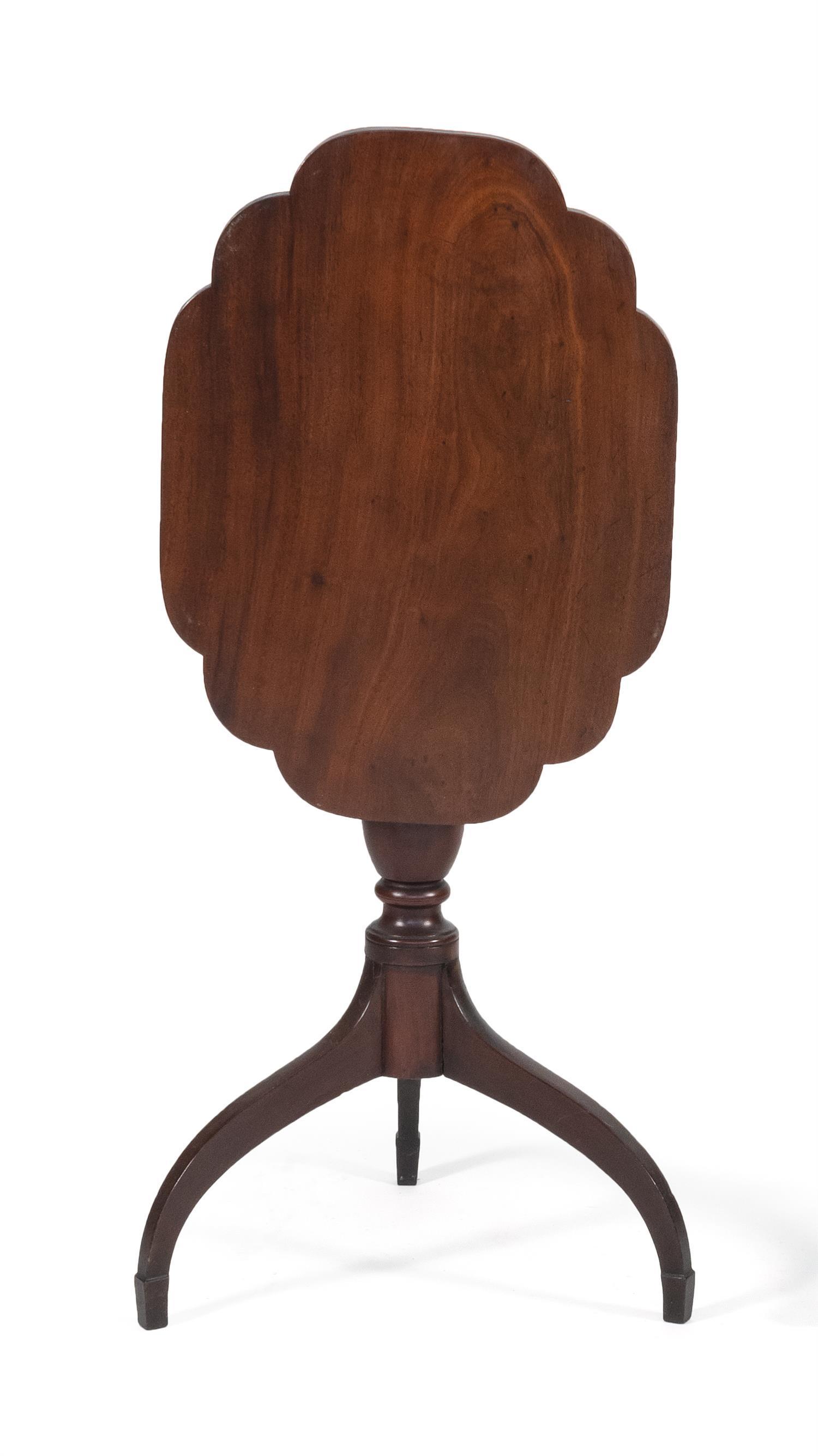 SHERATON TILT-TOP CANDLESTAND ATTRIBUTED TO THE: SHERATON TILT-TOP CANDLESTAND ATTRIBUTED TO THE WORKSHOP OF DUNCAN PHYFE New York, Circa 1795 In mahogany. Shaped top set on an urn-turned shaft raised on shaped legs ending in spade feet. Height 28.7