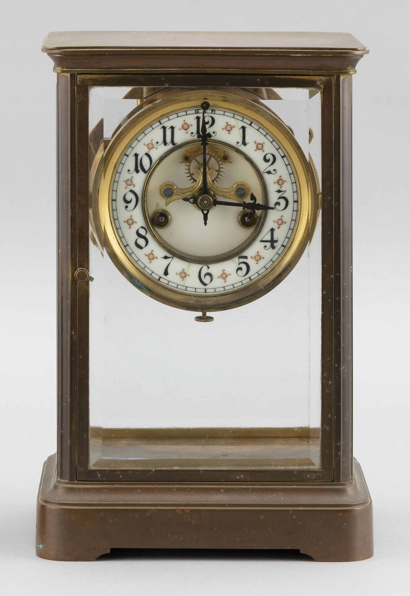 WATERBURY BRASS AND GLASS REGULATOR CLOCK Height 10.5”.: WATERBURY BRASS AND GLASS REGULATOR CLOCKBeveled glass case. Porcelain Arabic numeral dial. Faux mercury pendulum. Works signed and with patent date of September 13, 1898.Height 10.5”. Width 6.75”