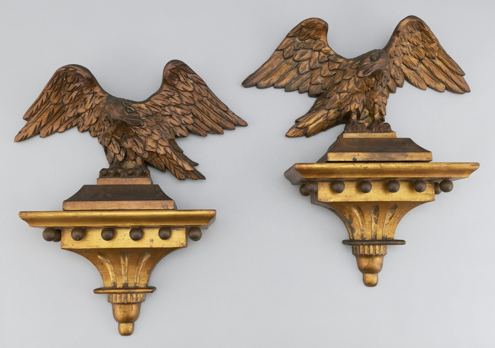 PAIR OF CARVED AND GILT WOODEN EAGLES ON WALL BRACKETS: PAIR OF CARVED AND GILT WOODEN EAGLES ON WALL BRACKETS 20th Century Total heights 17". Eagle widths 15".