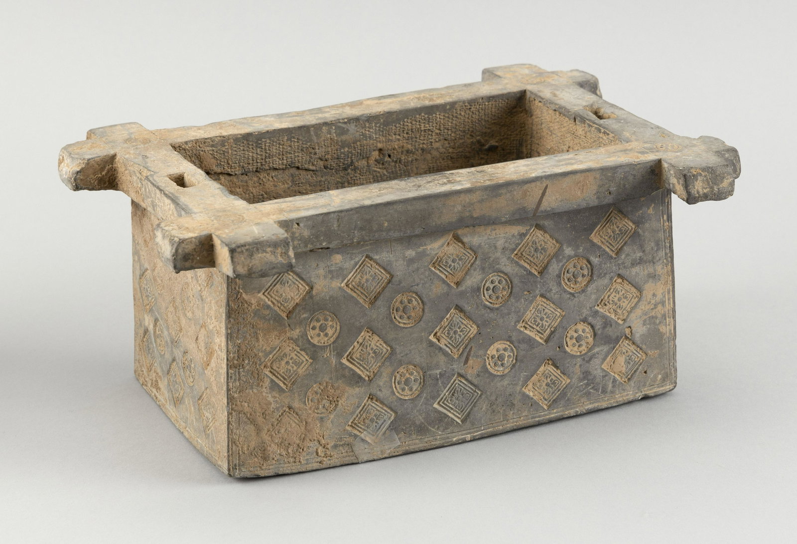 CHINESE POTTERY WELLHEAD Possibly Han Dynasty Height: CHINESE POTTERY WELLHEAD Possibly Han Dynasty Rectangular, with impressed square and circular mon decoration. Missing support rods and roof. Height 4.5". Length 7". Width 10".