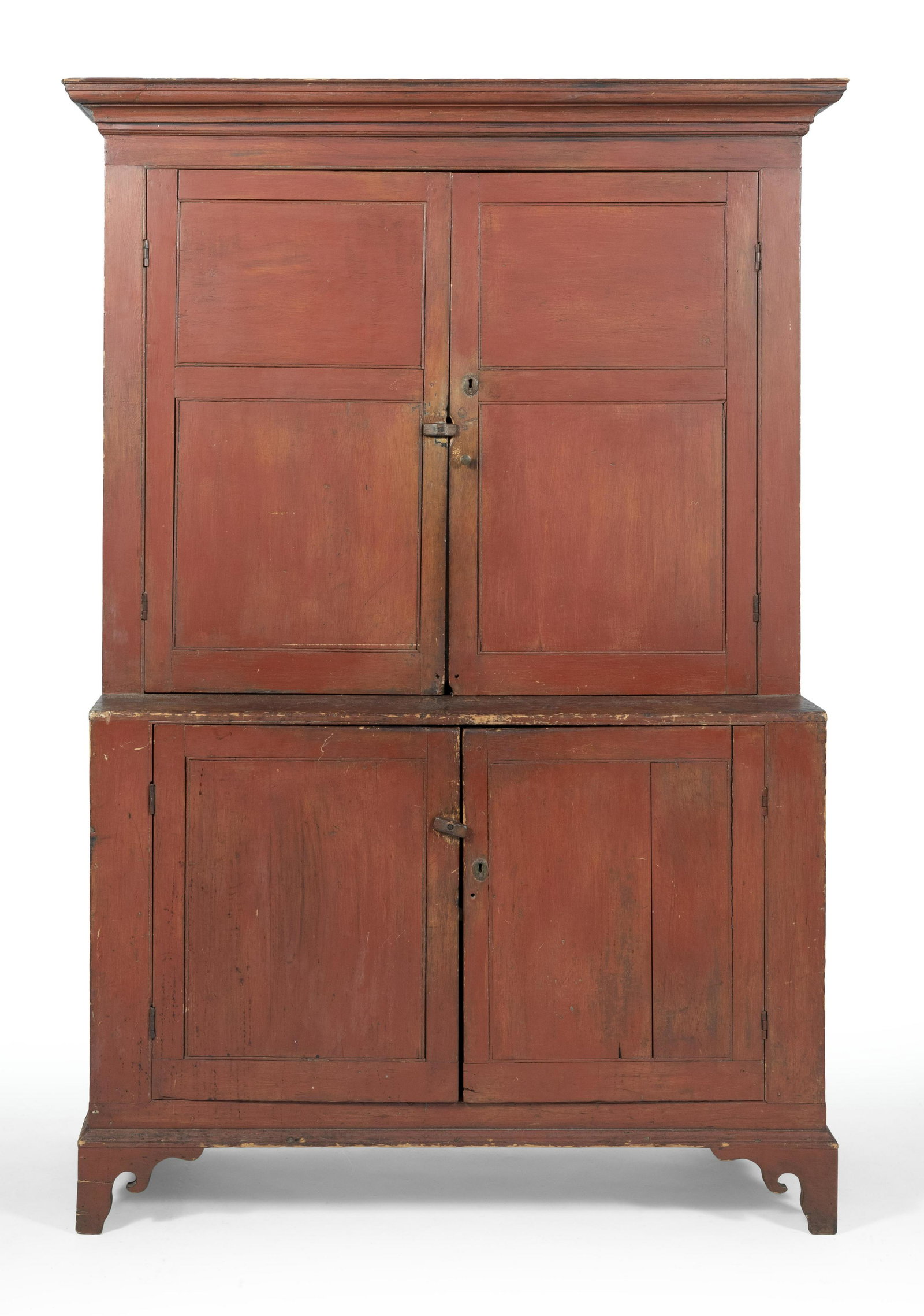 STEP-BACK CUPBOARD America, Early 19th Century Height: STEP-BACK CUPBOARDAmerica, Early 19th CenturyOne-piece construction. In pine under an old red wash. Molded cornice. Both sections with two paneled doors enclosing two interior shelves. Shaped bracket