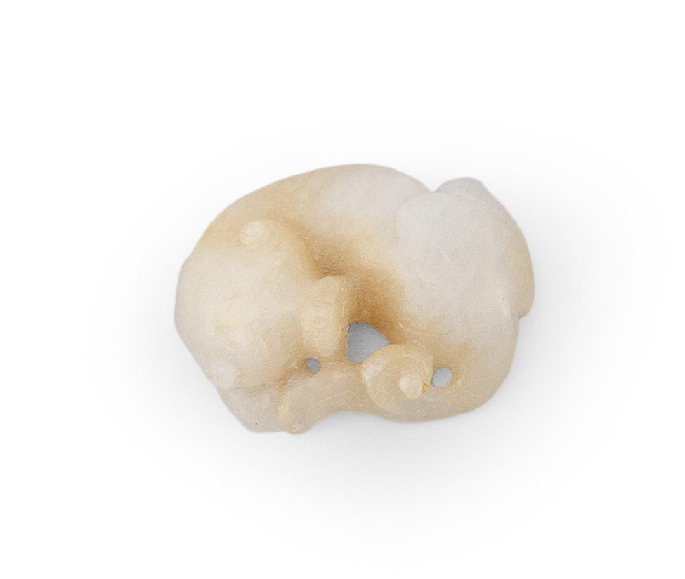CHINESE WHITE AND RUSSET JADE CARVING In the form of: CHINESE WHITE AND RUSSET JADE CARVING In the form of a reclining qilin. Length 2.4".