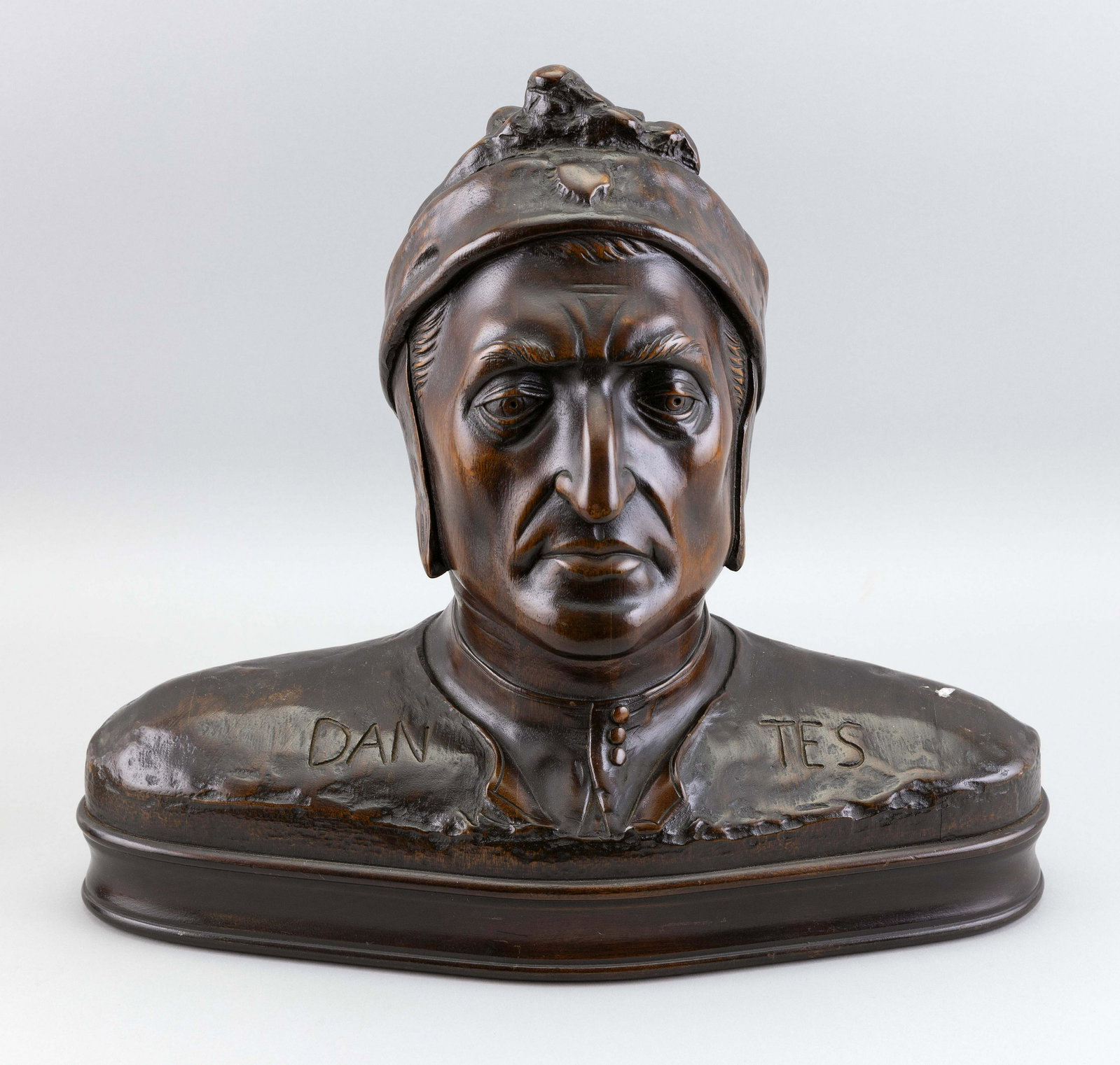 CARVED WOODEN BUST OF "DANTES" 20th Century Inscribed: CARVED WOODEN BUST OF "DANTES" 20th Century Inscribed “Dantes” across the shoulders. On a plinth base. Height 15”. Width 17”. Depth 7.75”.