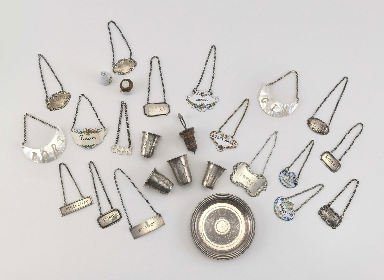 TWENTY-SIX PIECES OF BARWARE 1) Silver plated: TWENTY-SIX PIECES OF BARWARE 1) Silver plated engine-turned wine coaster. 2-12) Eleven assorted sterling silver bottle tickets, including two Tiffany & Co. for Brandy and Sherry. 13-16) Four Russian 8