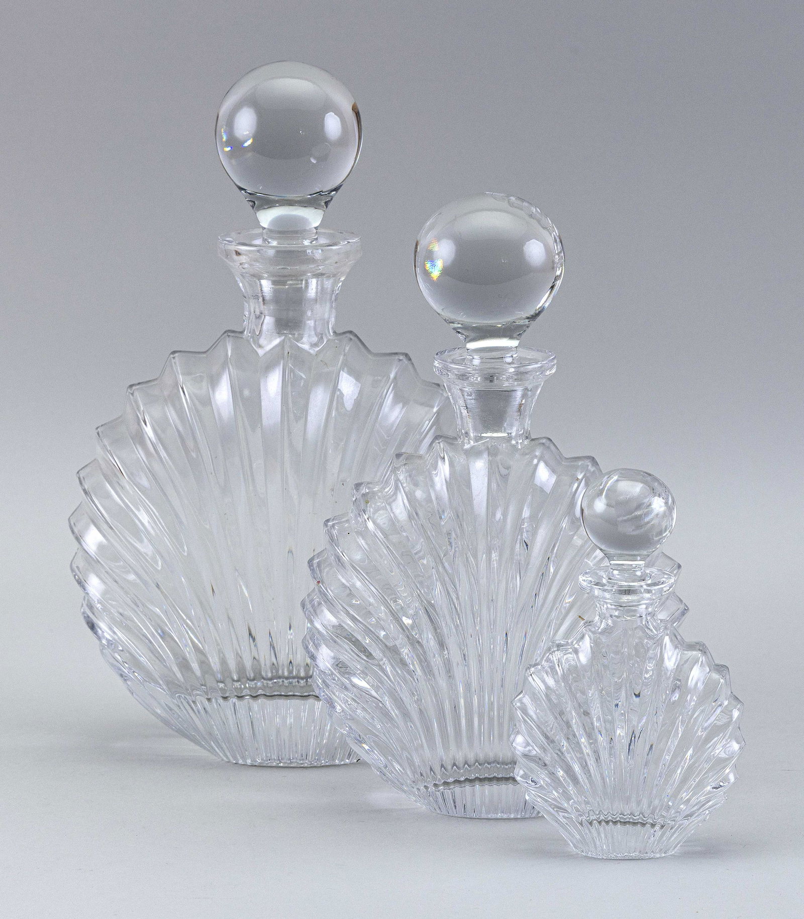 GRADUATED SET OF THREE SHELL-SHAPED GLASS DECANTERS (1 of 2)